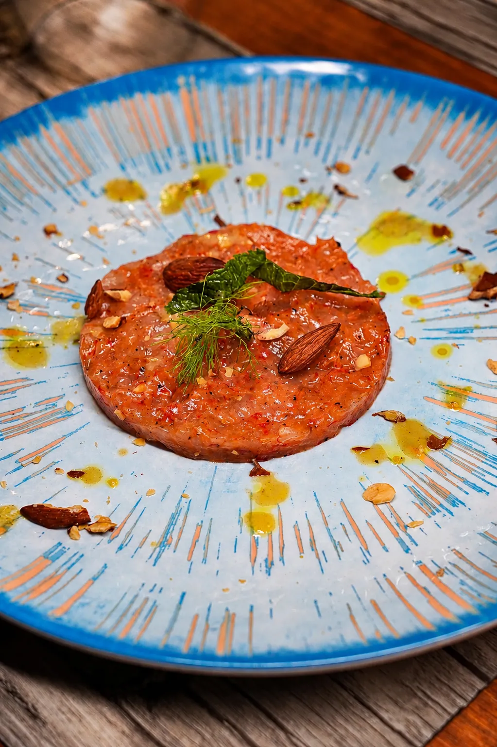 Tartare di tonno con finocchietto, menta e mandorle su piatto in ceramica blu